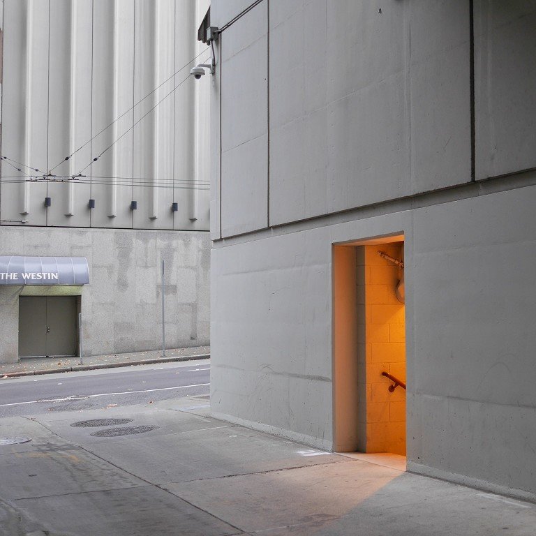  A doorway filled with warm light on a cool white building. 