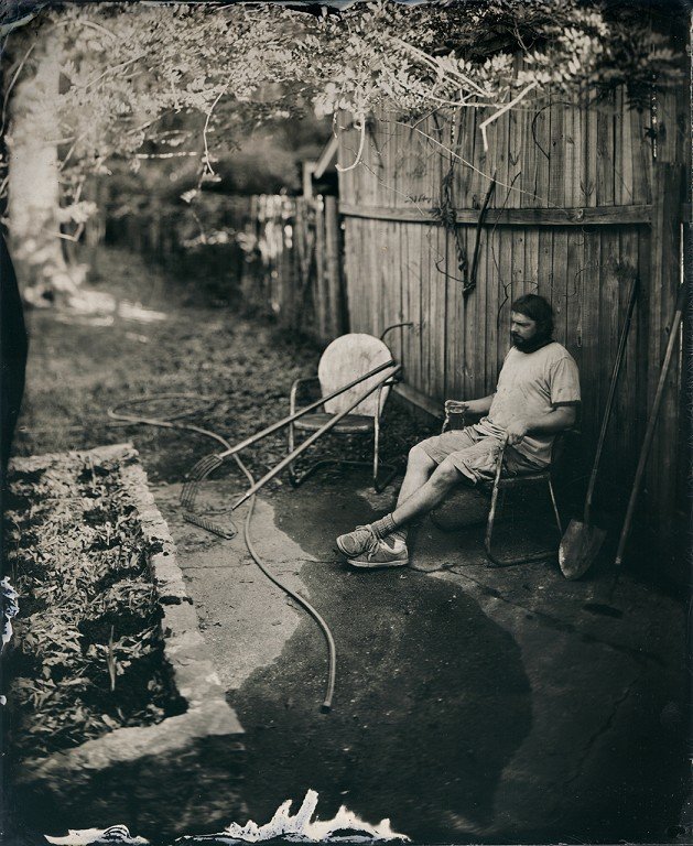  A black and white photo of a person sitting in a lawn chair. 