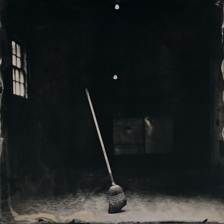  A black and white photo of a broom in a dark room. 