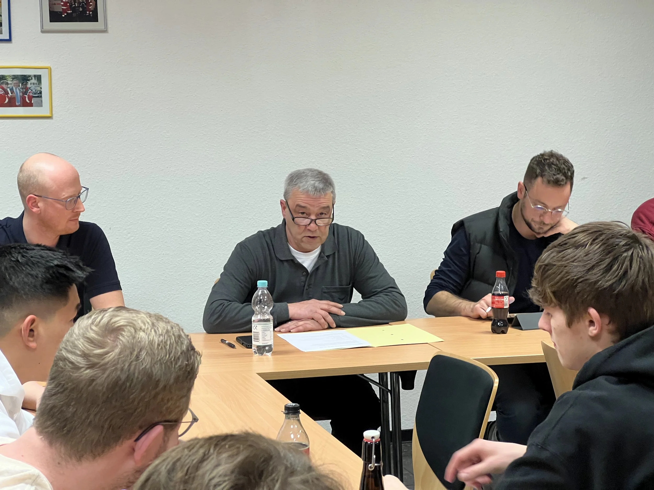 Gruppe von Menschen bei einem Meeting an einem Tisch, mit Papieren und Getränken.