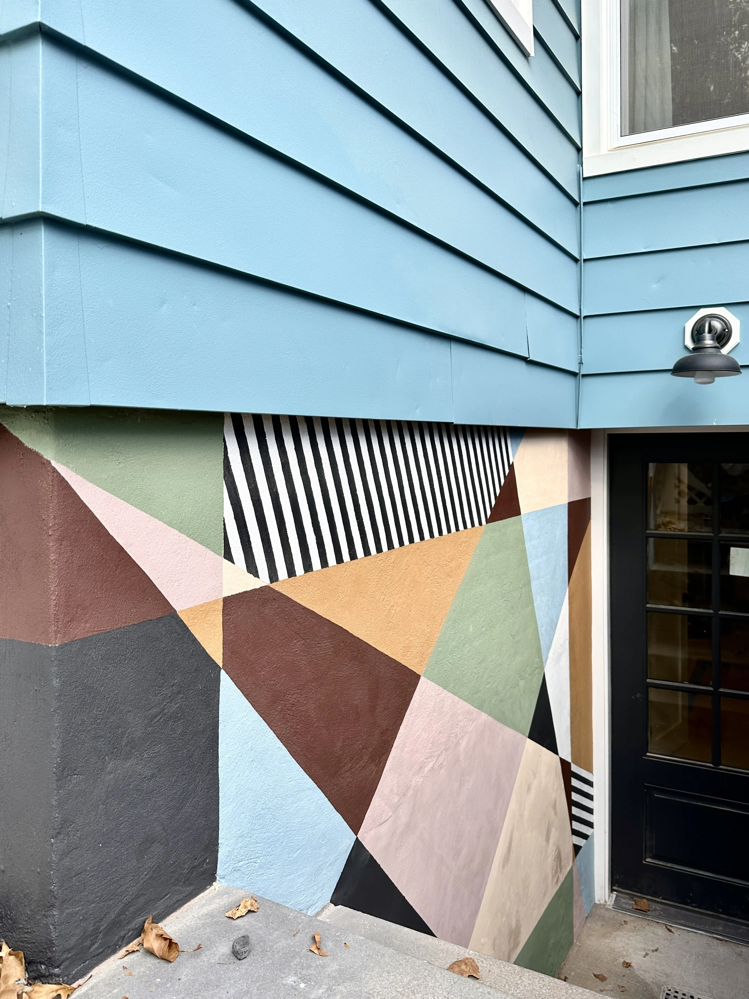 Colorful stairwell wall mural with earthy tones and playful shapes, designed to add curb appeal to a basement entrance