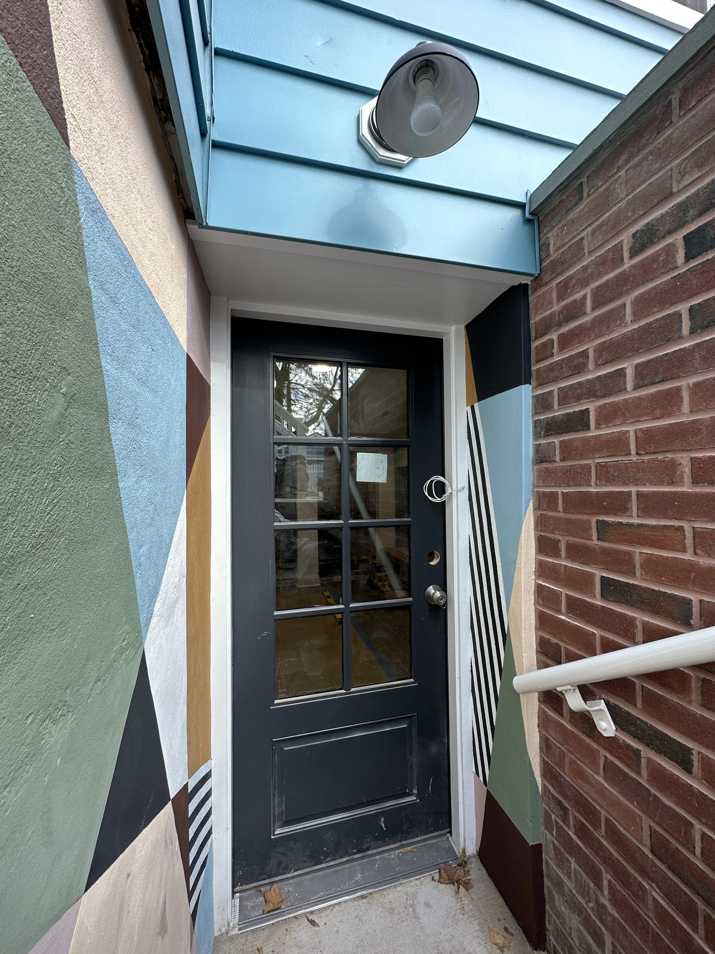 Custom exterior mural by Shapes For The People, using earthy colors and bold shapes to bring character to a basement stairwell.