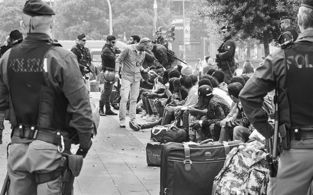   Milan   Dozens of refugees are stood over by police conducting ‘routine’ checks.  