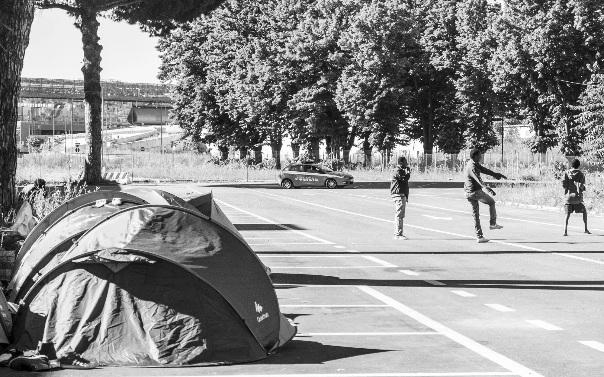   Checking In    Police perform a drive by at one of the known make-shift camps in Rome while boys play soccer by their tents. 