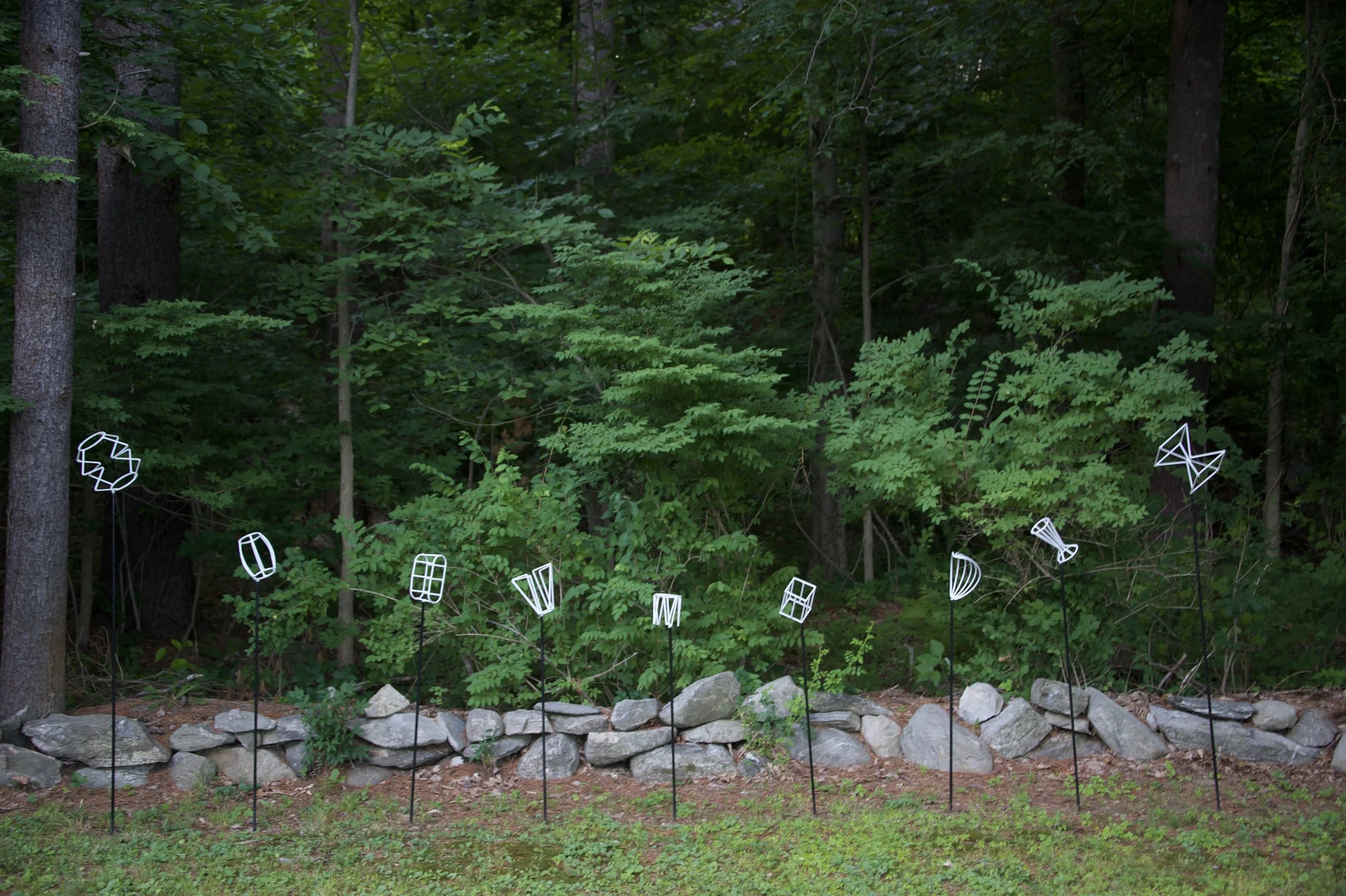 outdoor installation of white, abstract metal sculptures in the summer