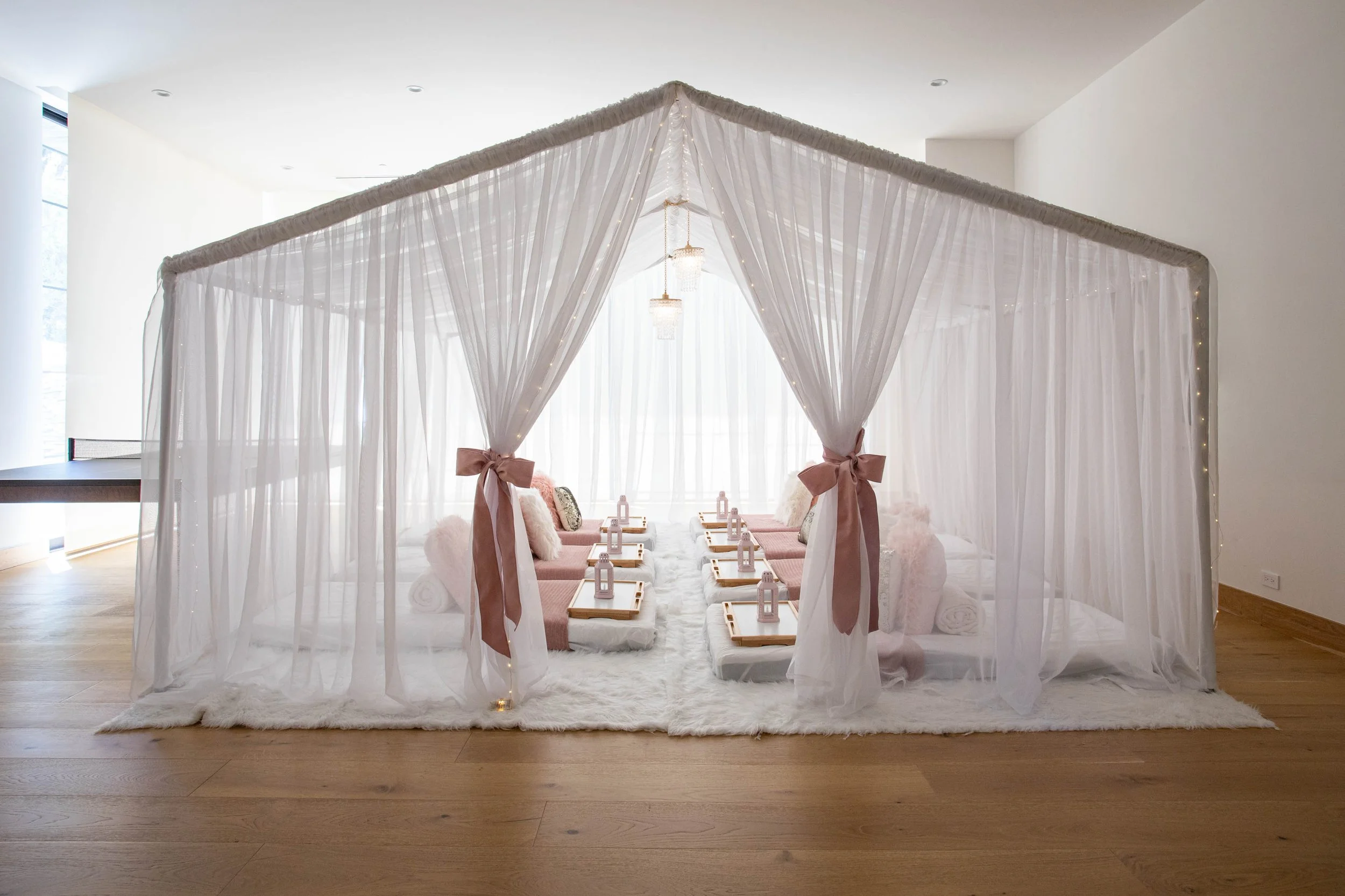 Beautiful draped canopy structure with sleepover mattresses and cushions inside.