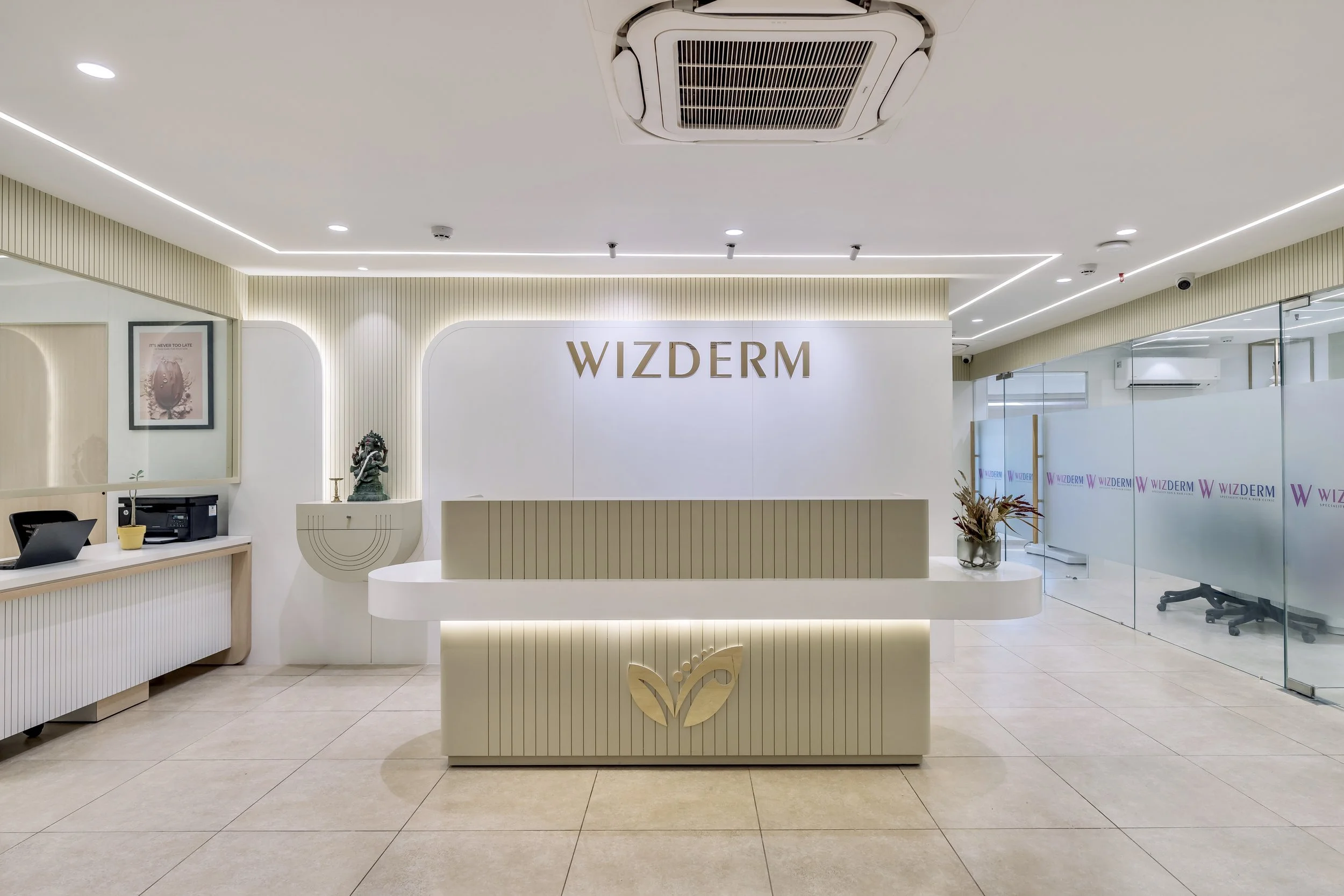 Modern reception area of Wizderm with a white and beige color scheme, a reception desk featuring a leaf logo, a wall with the Wizderm logo, and a glass partition with the company name.