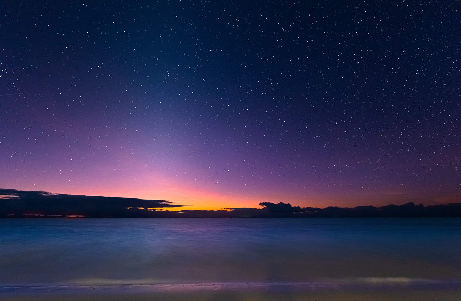 colourful early sunrise on the beach with stars still visible