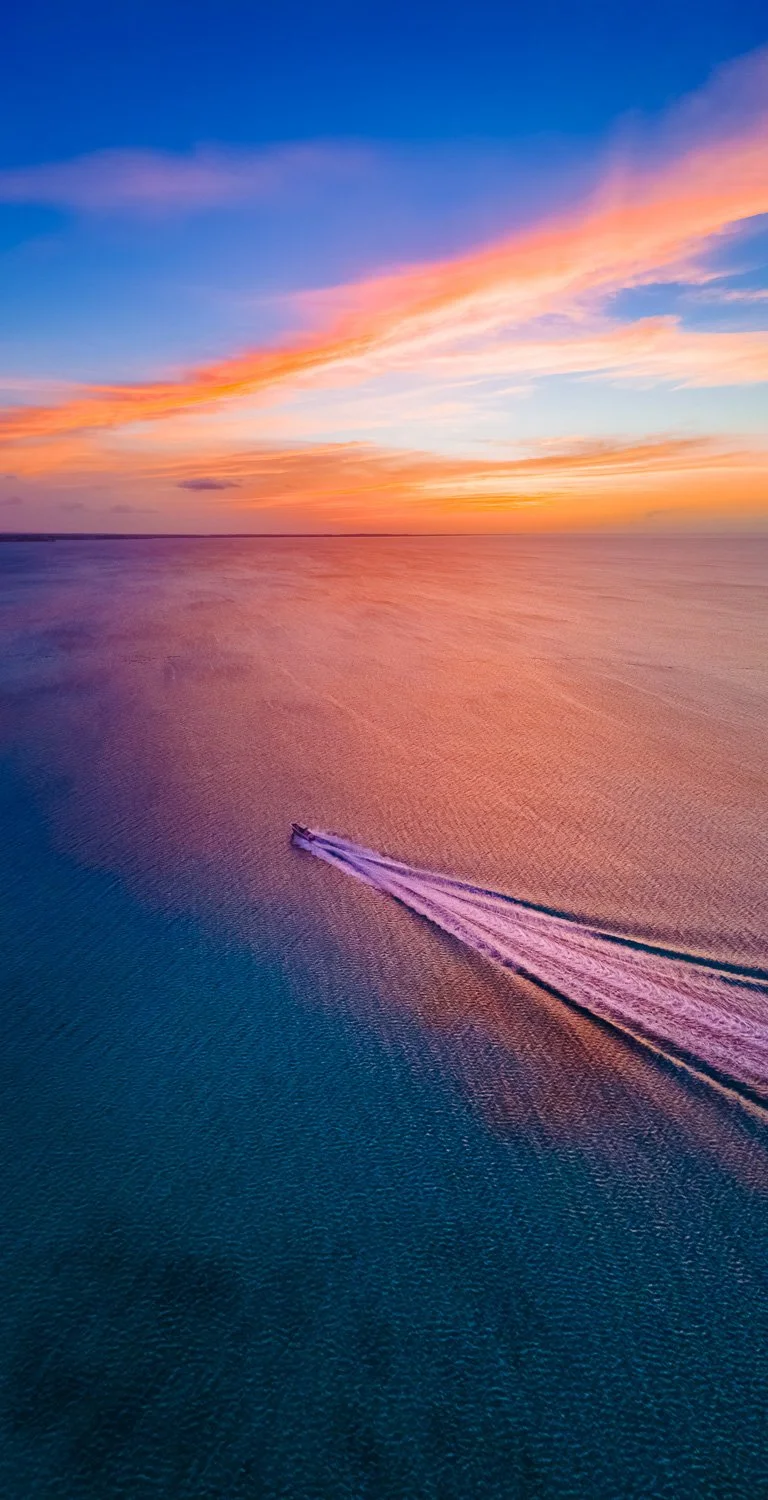 boat sailing into colourful sunset - drone photography how to