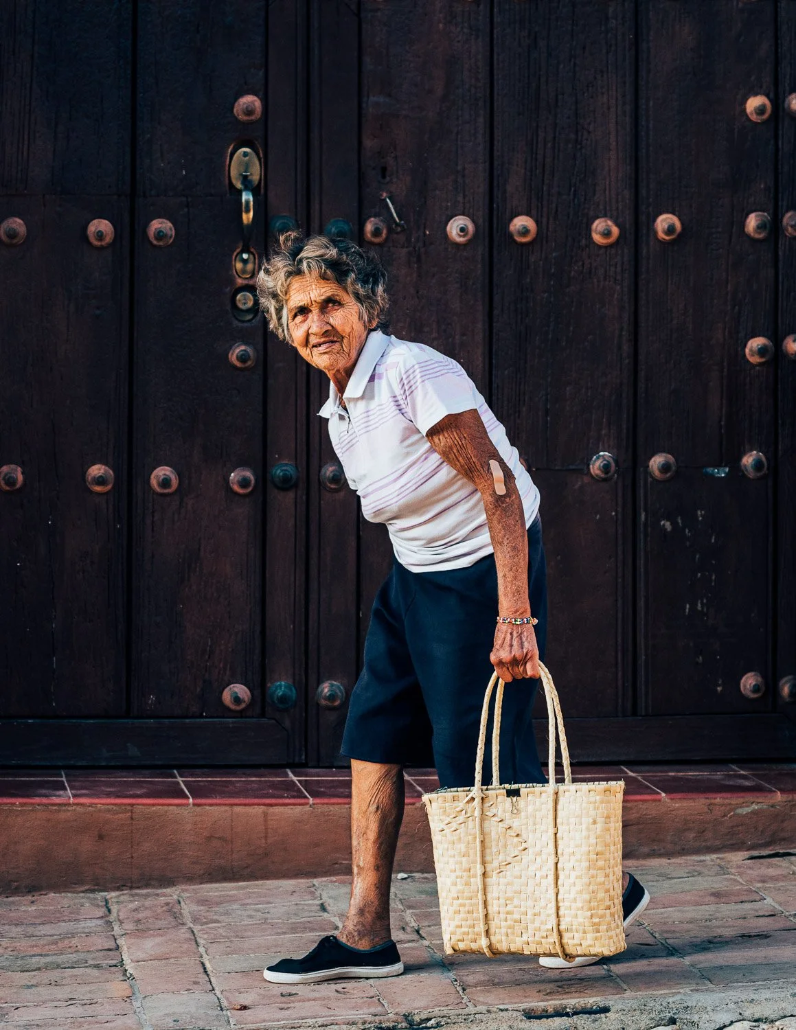 Old woman walking on street in Trinidad - visiting Cuba from USA