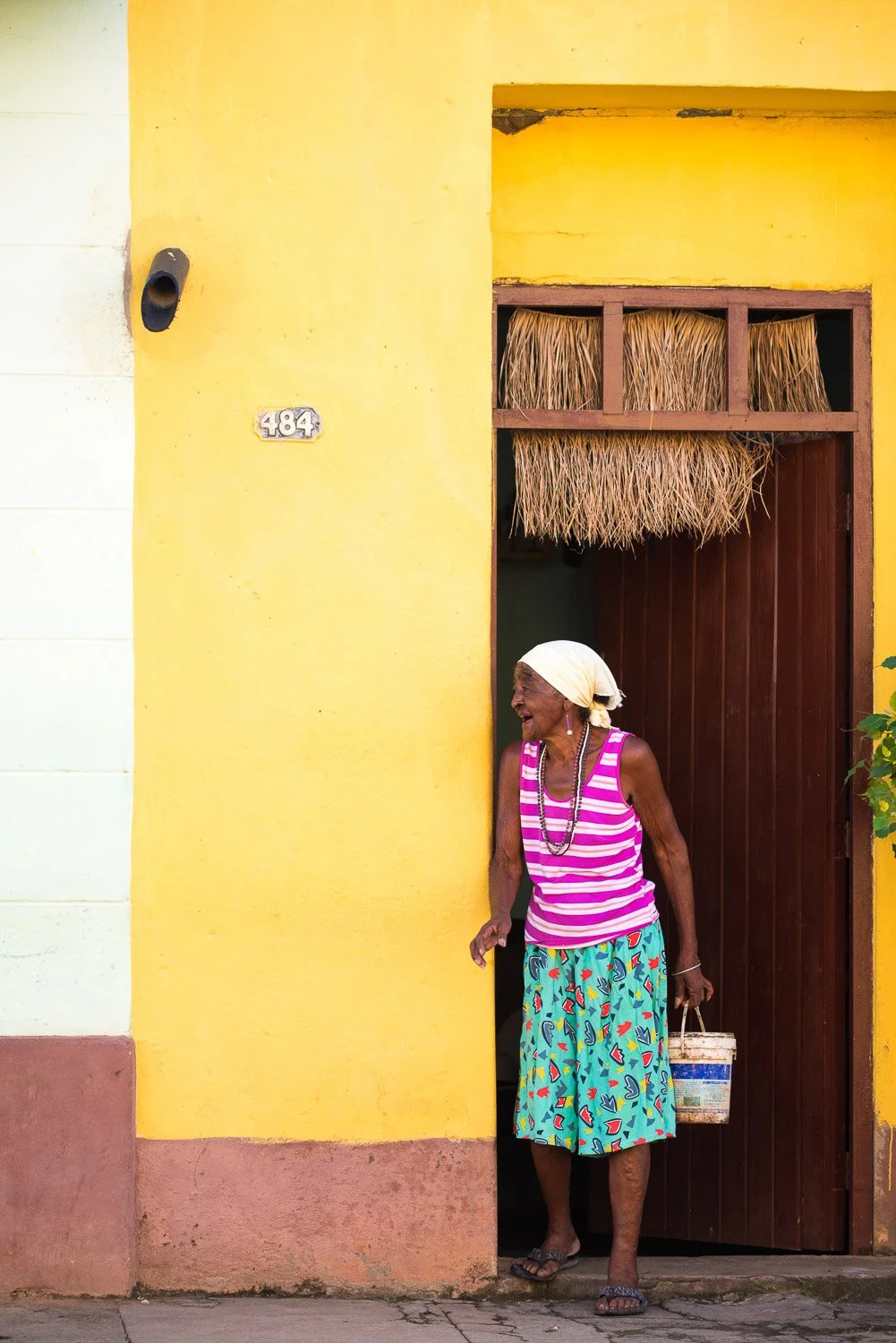 Black woman leaving home in colorful dress - visiting Cuba from USA