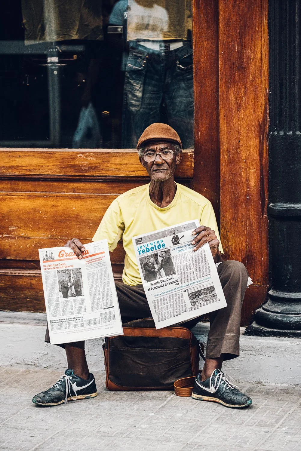 man selling newspapers on sidewalk - visiting Cuba from USA