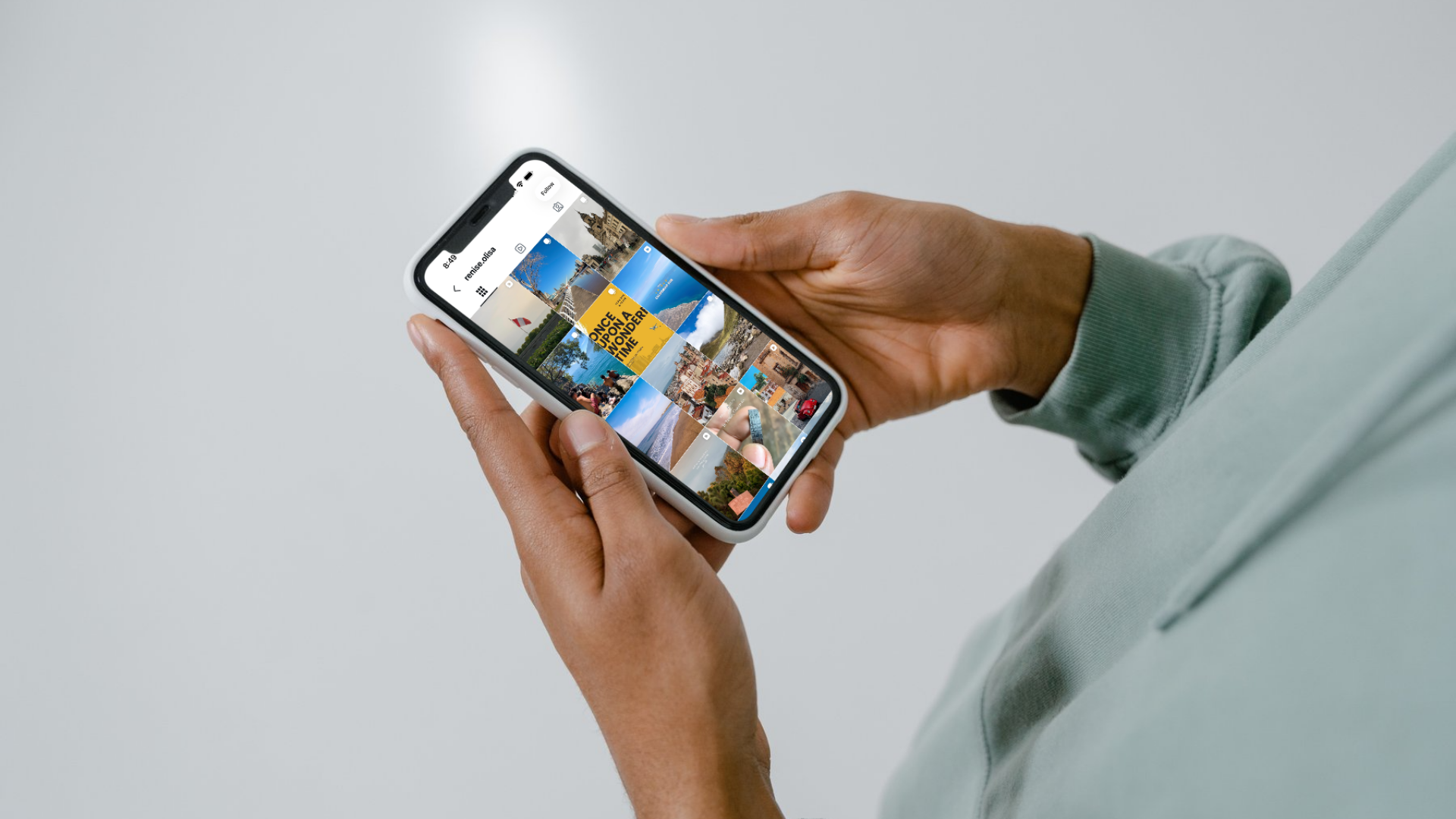Person holding an iPhone displaying an Instagram grid of photos and Reels.