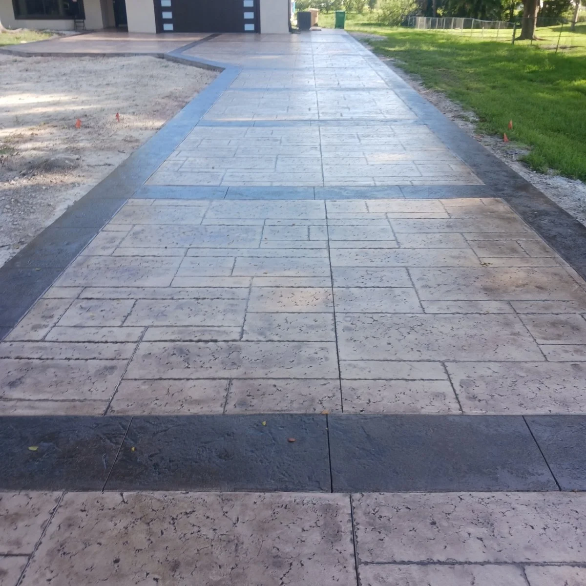 Stamped concrete driveway with decorative patterns and bordered edges.