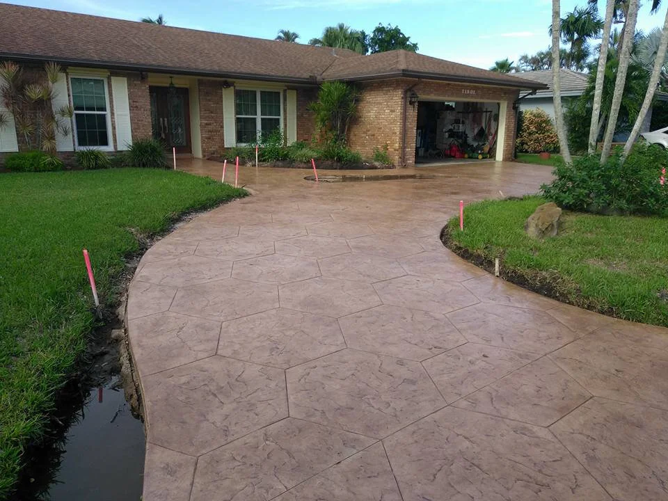 A house with a patterned decorative stamped concrete driveway and a neatly maintained lawn.