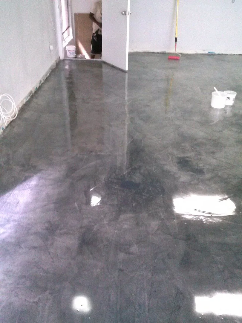 Interior space with polished concrete floor, white walls, an open door, a broom, and paint or maintenance supplies.