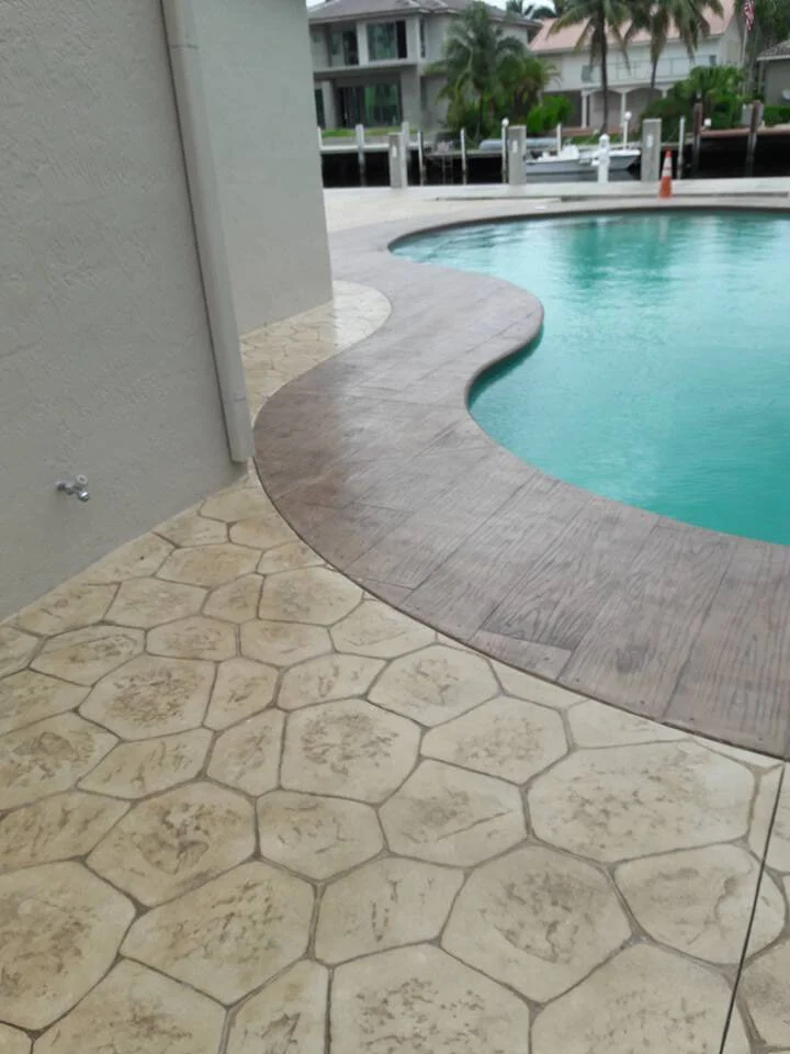 Decorative stamped concrete deck and patio using colors and textures surrounding swimming pool.