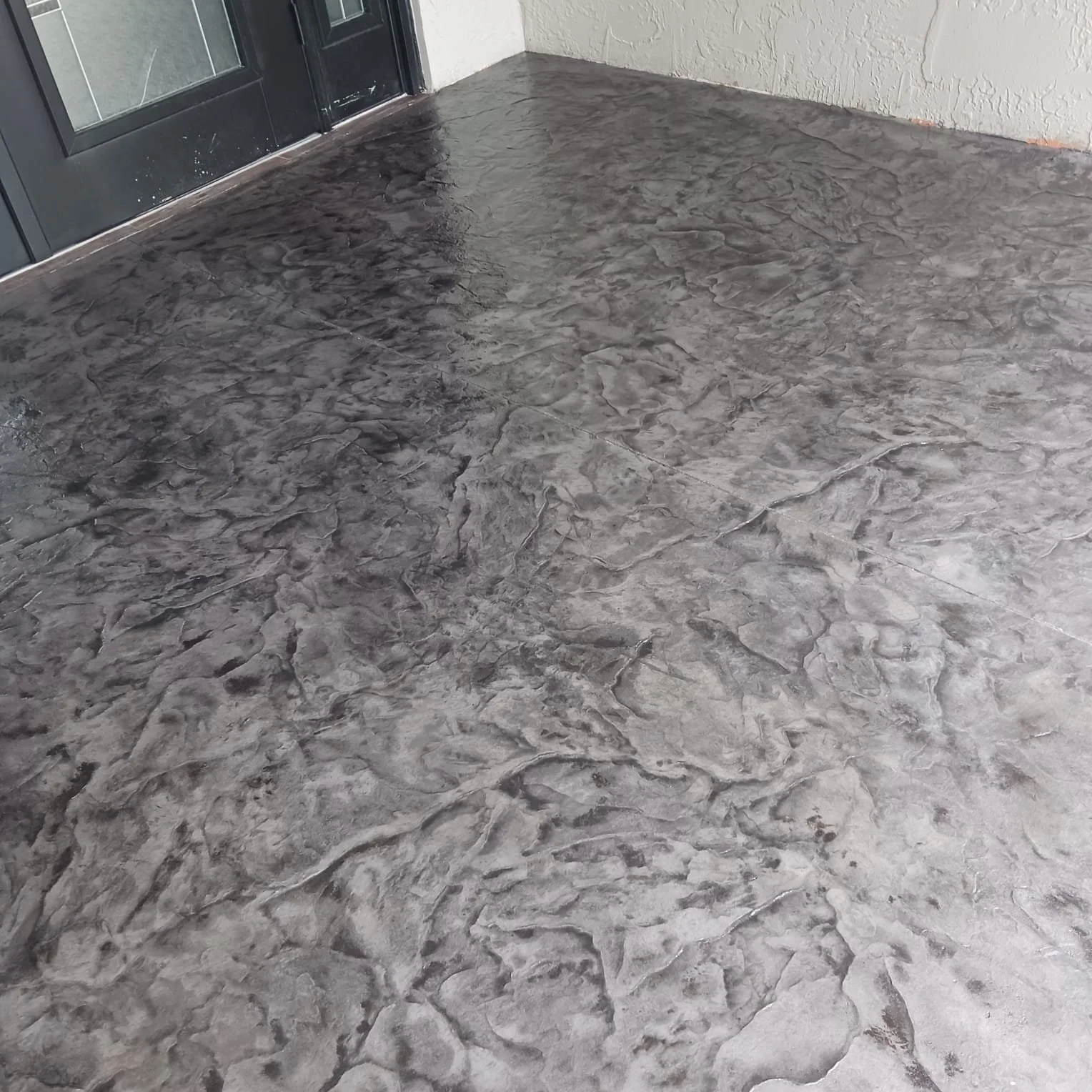 Close-up of a polished, textured gray concrete floor near a doorway with a dark frame.
