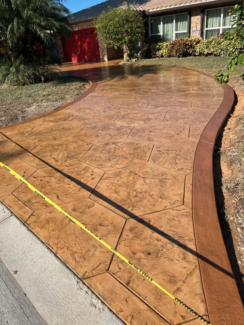 Stamped concrete driveway on a residential home with Beige colors and side ribbons of decorative concrete.