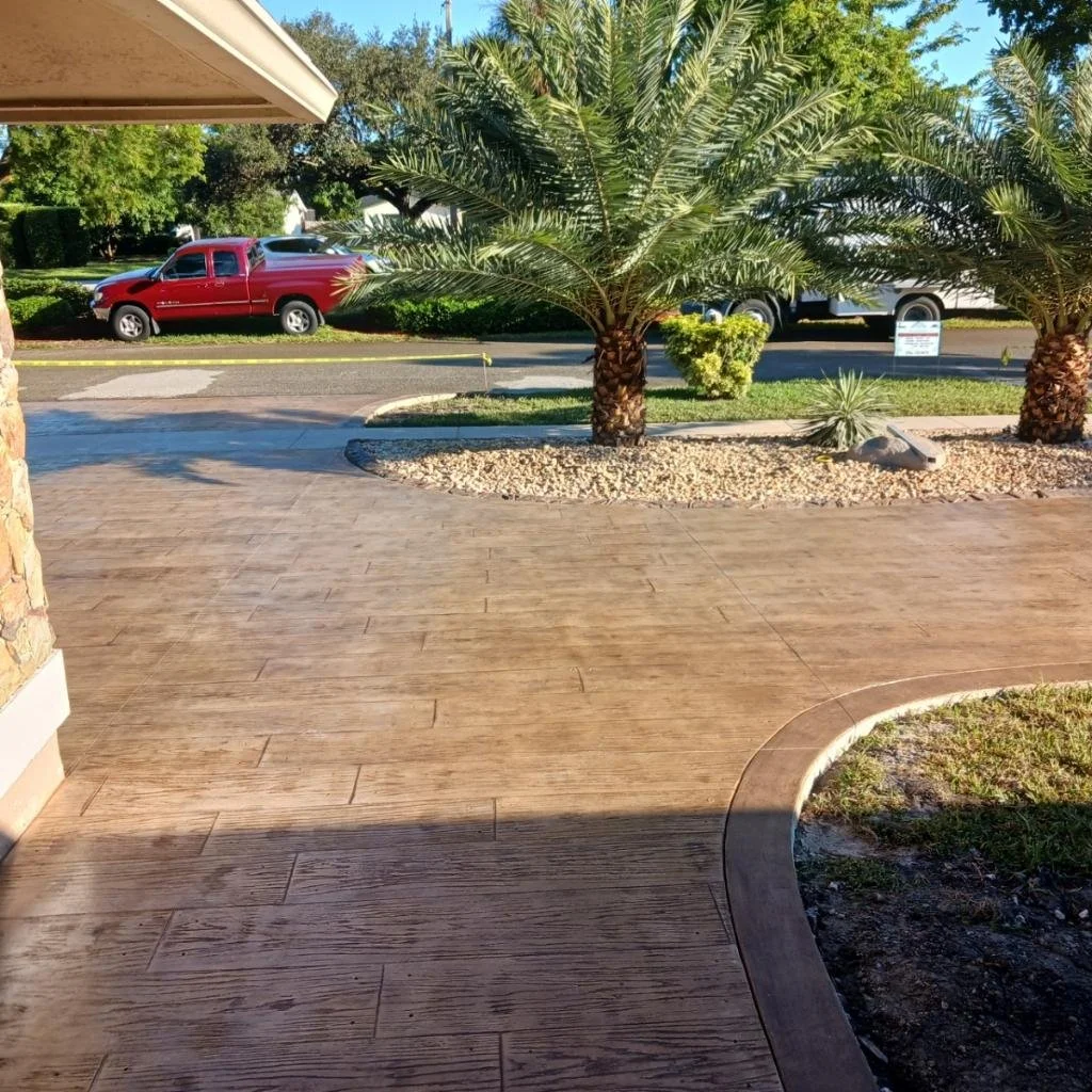 Front yard with palm trees and a concrete driveway, adjacent to a street with a parked red pickup truck.