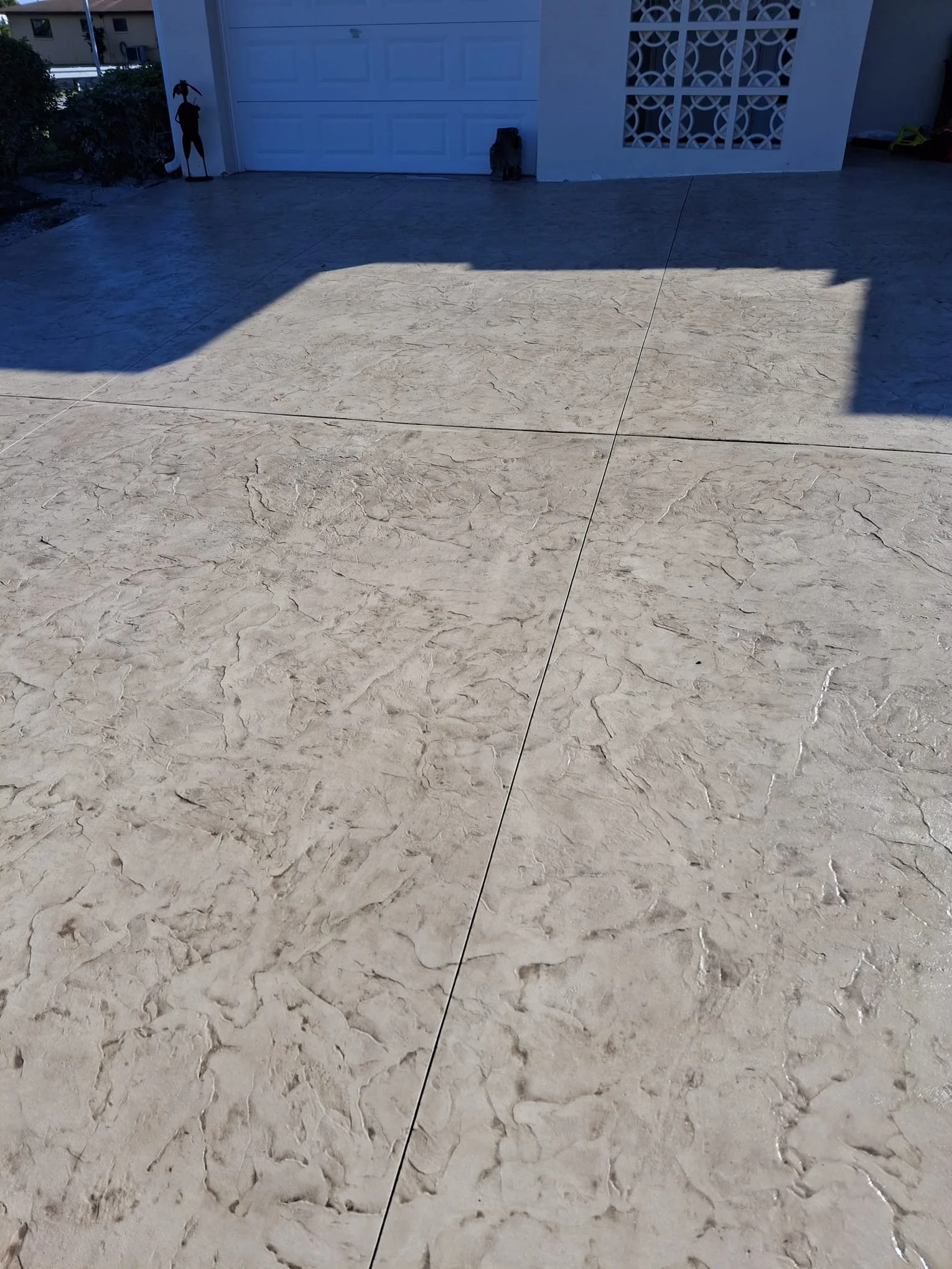 Stamped concrete driveway leading to a white garage with decorative wall features.
