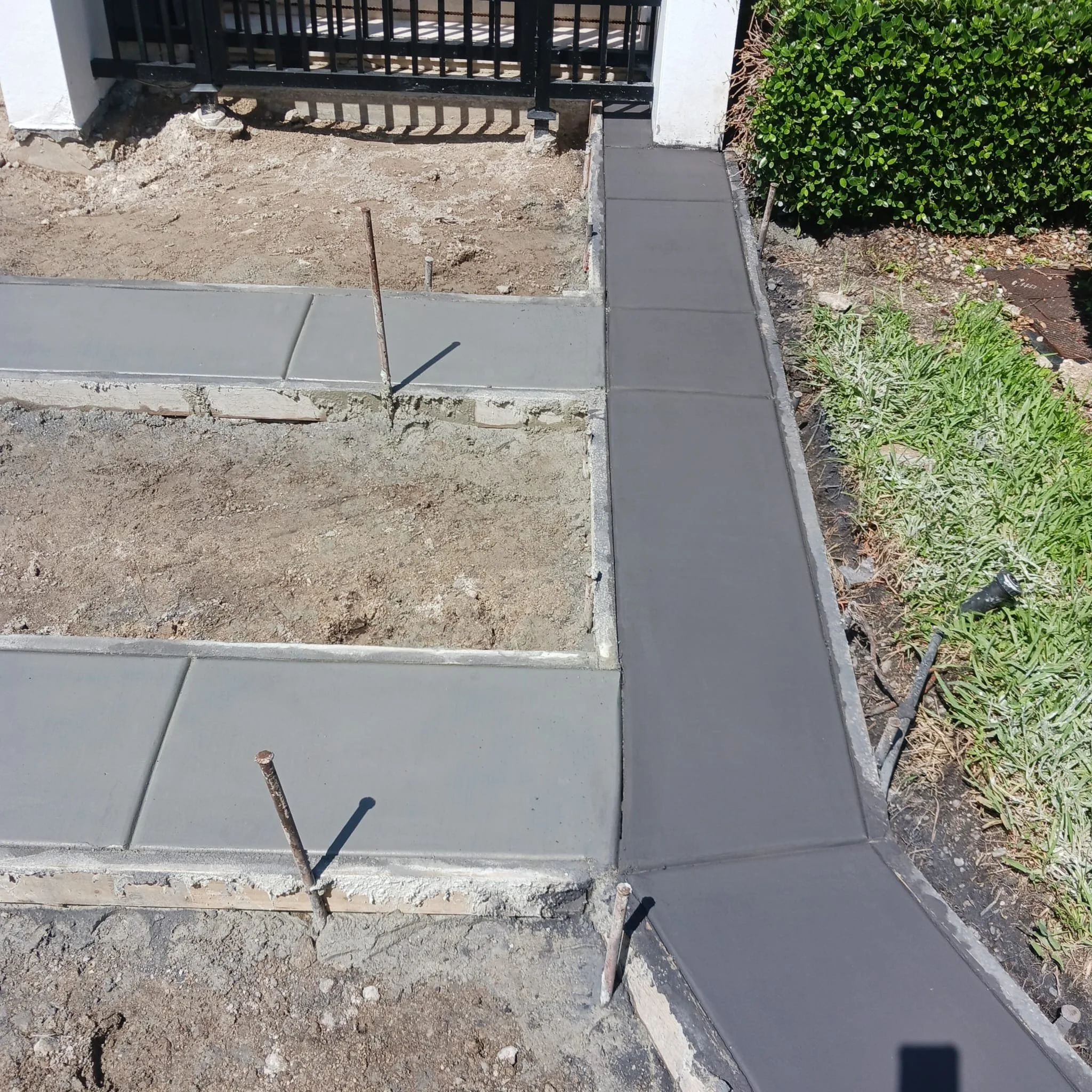 Freshly poured concrete driveway ribbons being prepped for textured stamping.