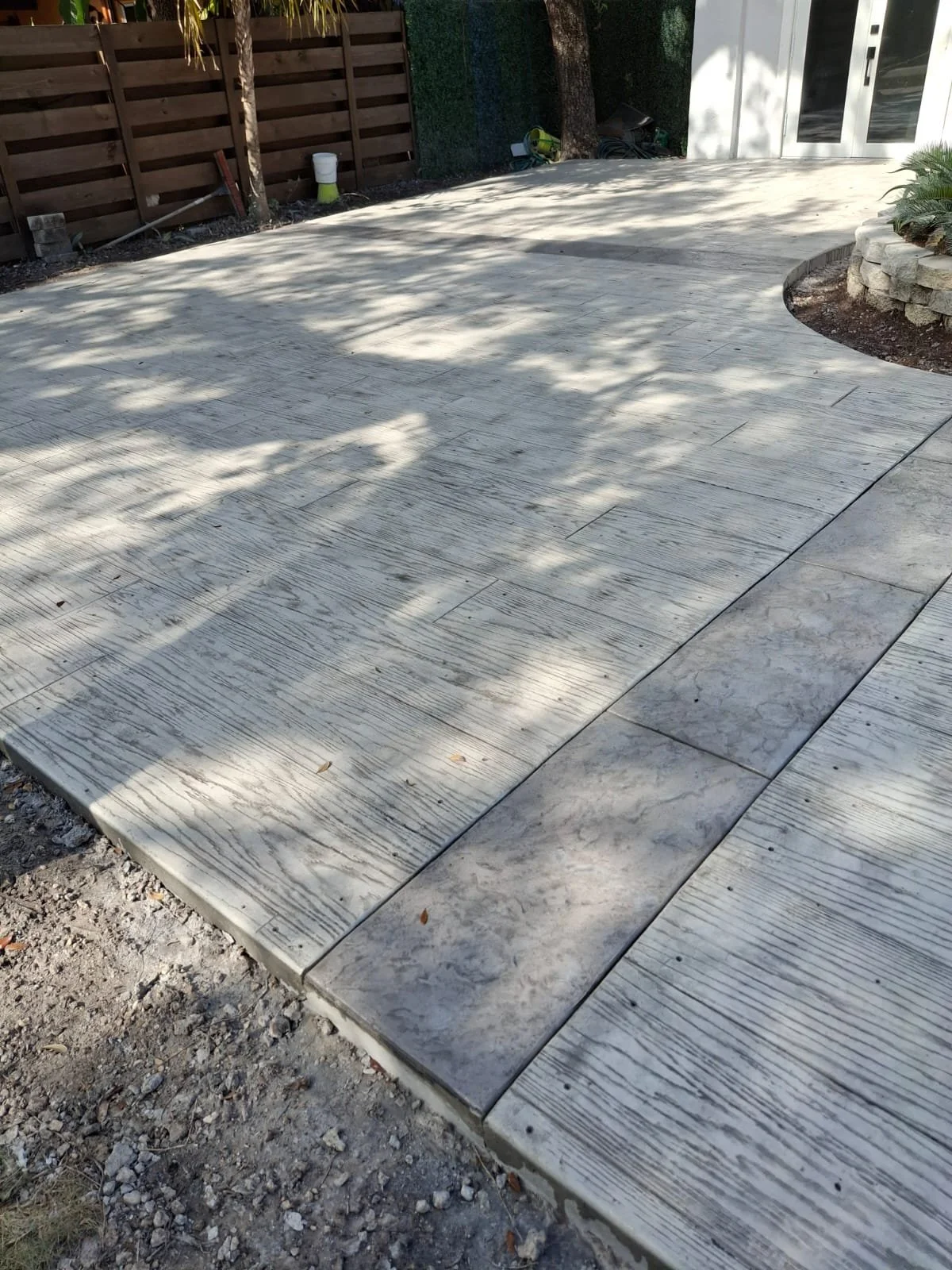 Textured concrete patio with wood fence and garden