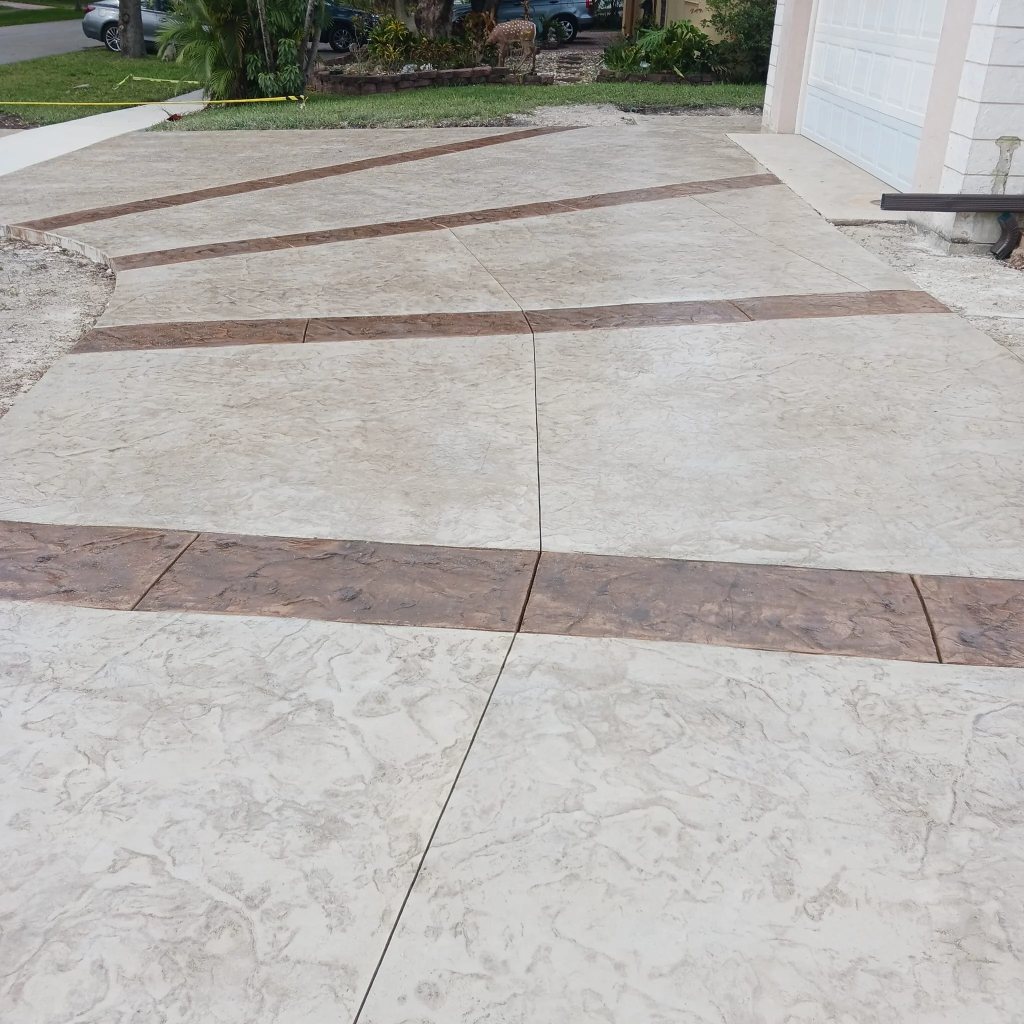 Stamped concrete driveway with decorative patterns and different color sections.