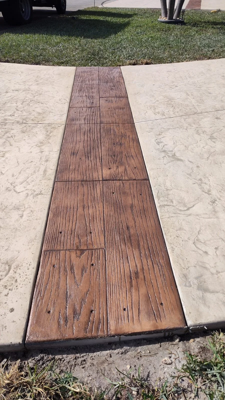 Decorative stamped concrete driveway and walkway with colored wood texture patterned ribbons throughout.