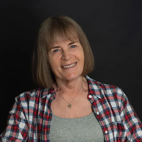 Photo of Zoe Playdon, who has midlength brown hair and is wearing a checked shirt