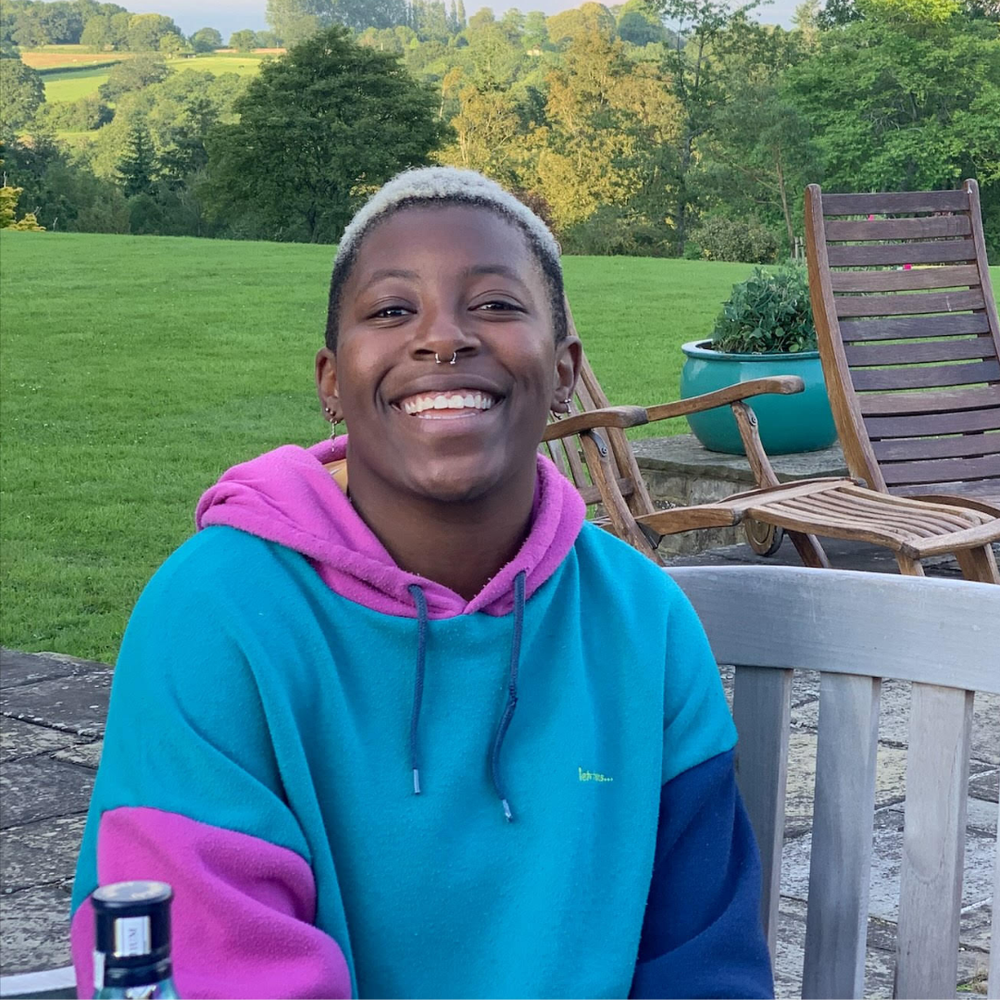 Elz, a Black person with short bleached hair and a huge smile