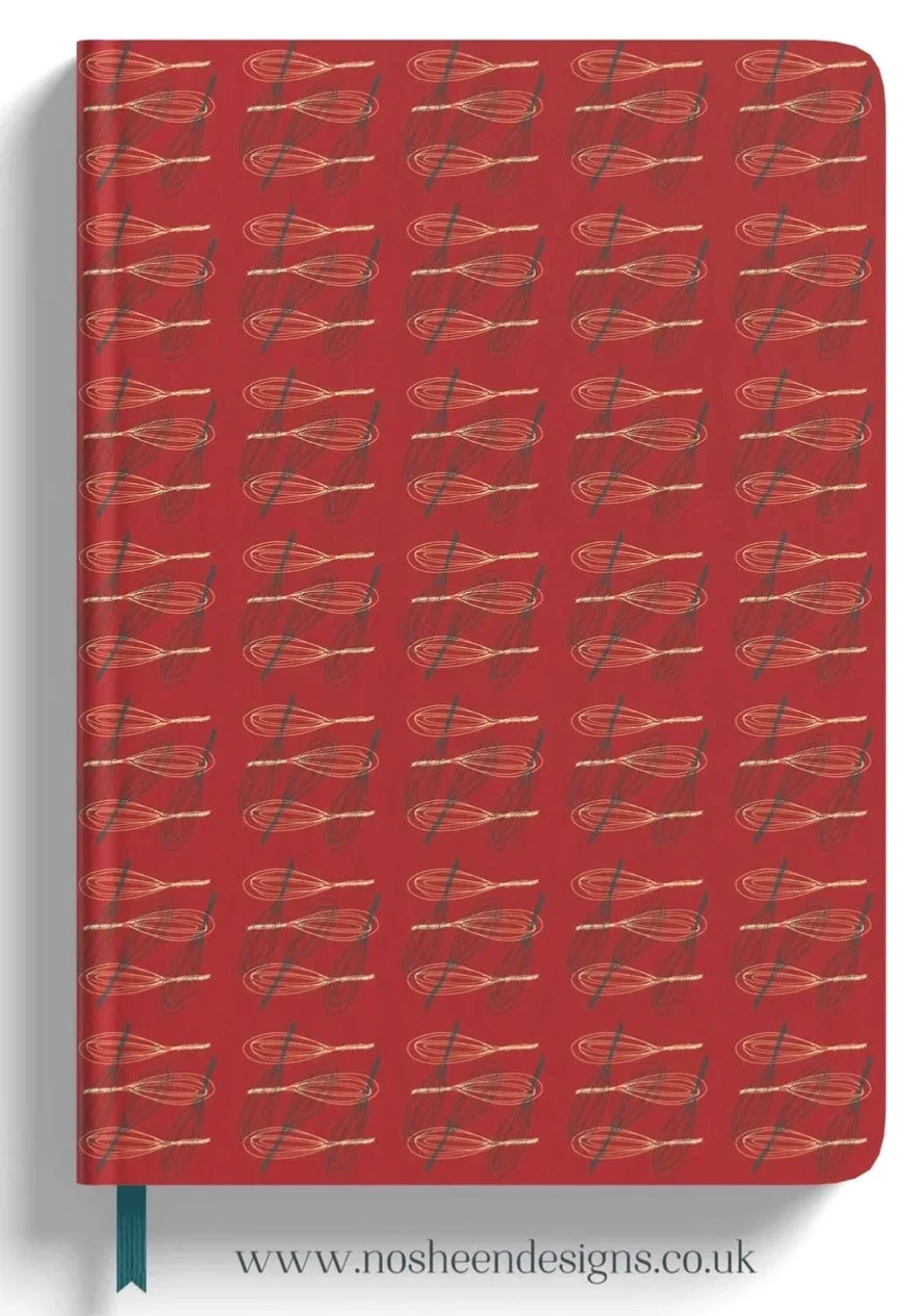 Red notebook with a repeating pattern of gold and silver whisks, and a teal ribbon bookmark, with the website 'www.nosheendesigns.co.uk' at the bottom.