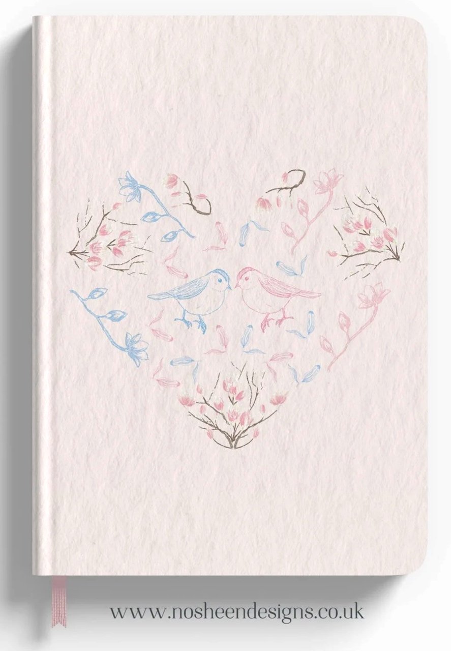 A white notebook with a pastel-colored drawing of two birds facing each other in the center, surrounded by branches, leaves, and small flowers, forming a heart shape. The notebook has a pink ribbon bookmark and the website www.nosheendesigns.co.uk printed at the bottom.