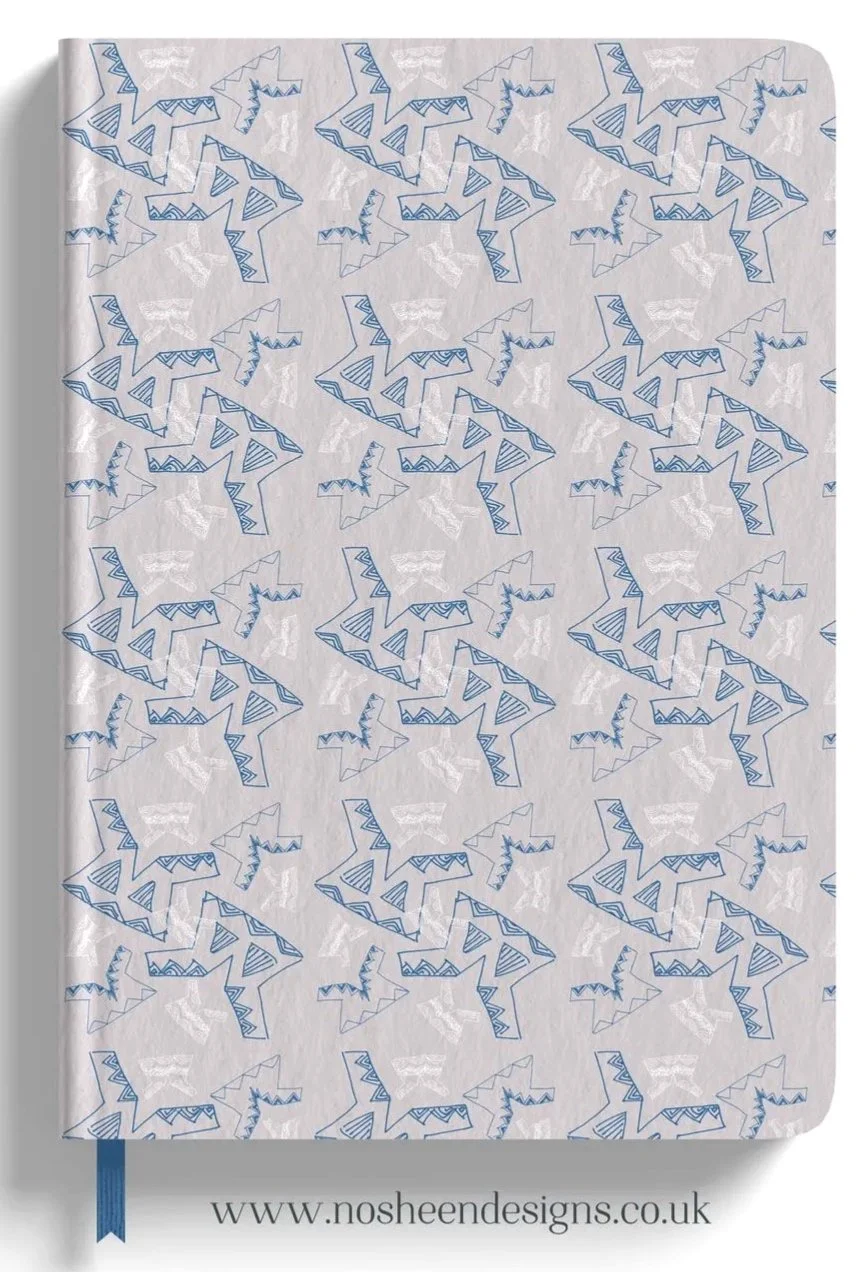 Notebook page with a pattern of blue and white cartoon dinosaurs, featuring geometric shapes, and a blue ribbon bookmark at the bottom.