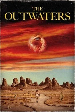 Movie poster for The Outwaters, depicting the Mojave Desert with an orange sky, and a bloodied white person’s face in a circle where the sun should be. Below, there is a road and cacti, and a white girl in shorts walking towards an outcrop of rocks.