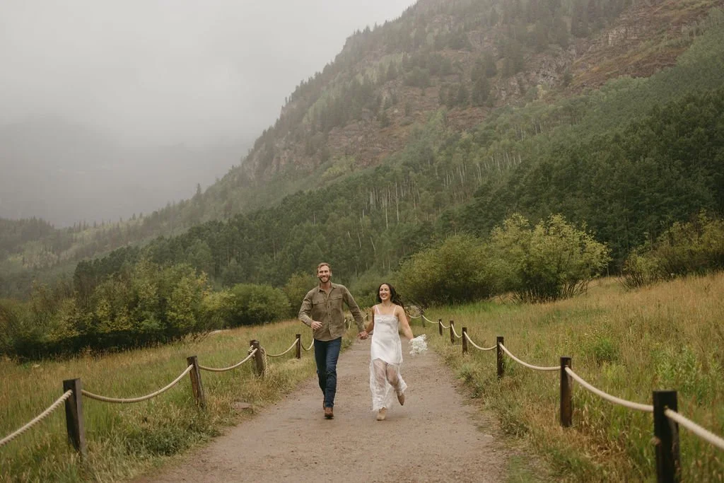 An engaged couple frolics along a path in the Maroon Bells during their Aspen, CO engagement session.