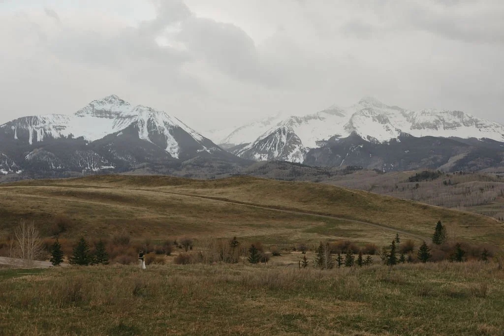 Newlyweds snuggle up beneath snowcapped mountains during their early Spring Telluride elopement.