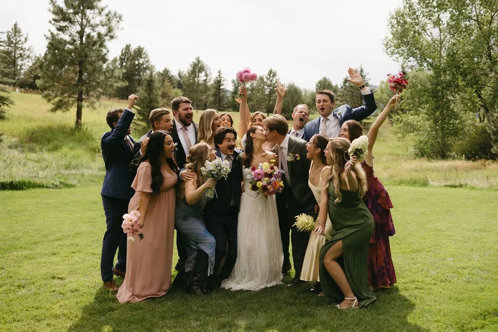 A colorful wedding party cheers for the bride and groom during wedding party portraits.