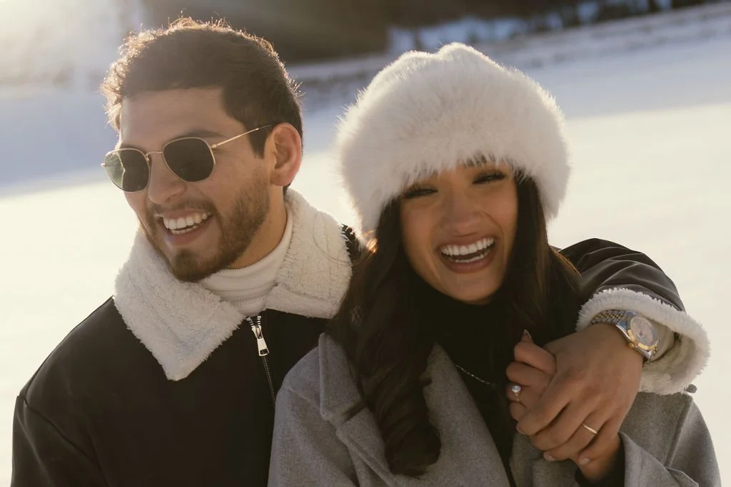an engaged couple cozies up in the snow following their engagement