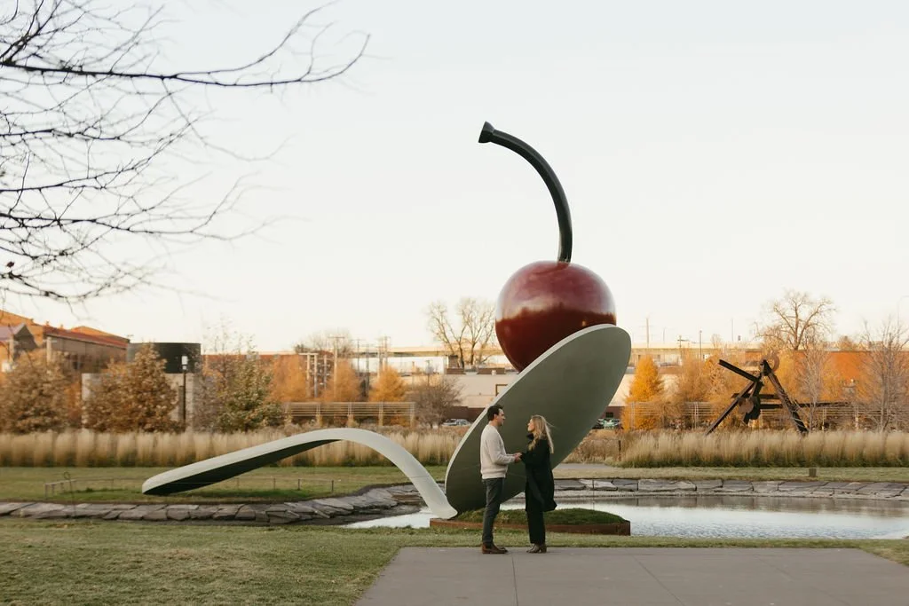 a man prepares to propose to his girlfriend in front of the Minneapolis Spoonbridge and cherry