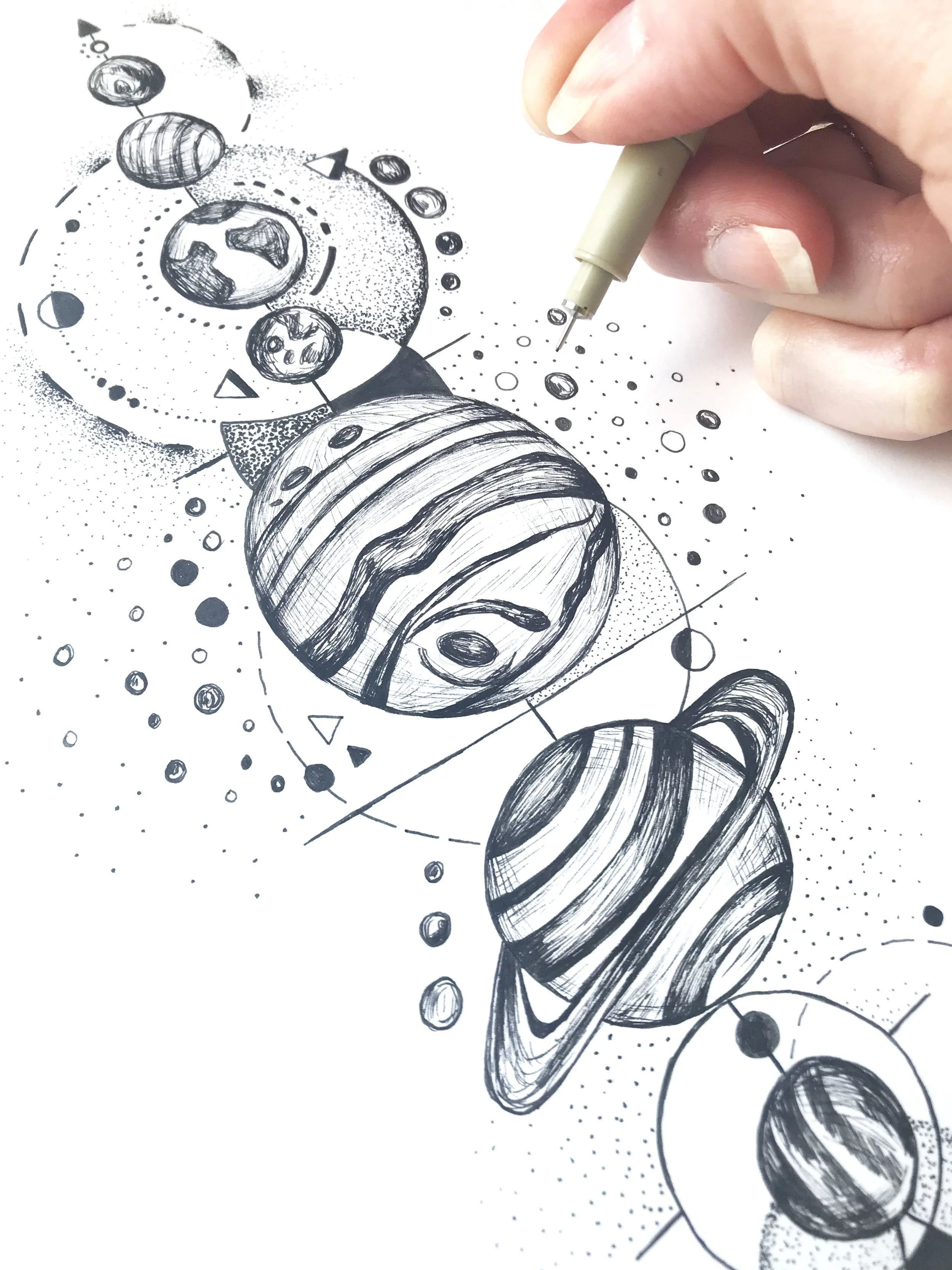 Space tattoo design with planets, stars and comets drawn in pen and ink on paper.
