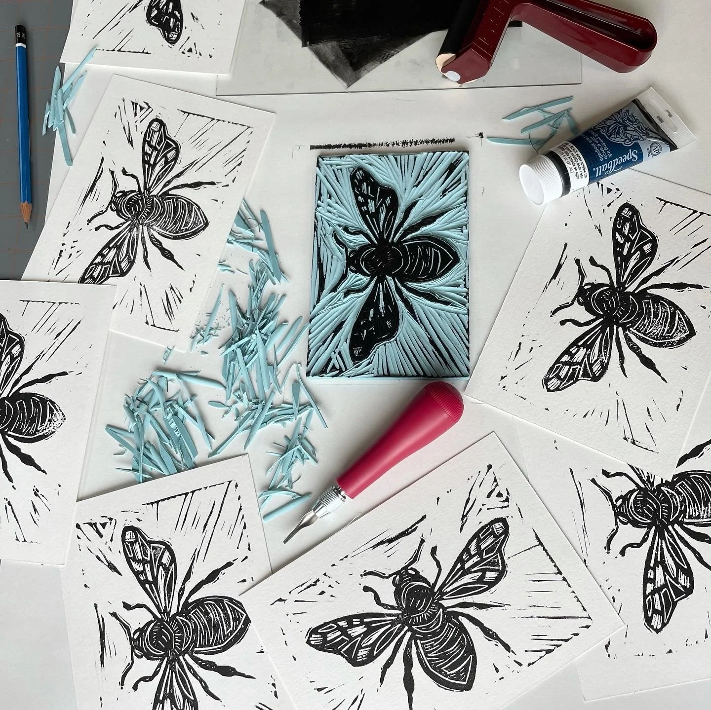 Lino cut carving of a honey bee with prints made using black ink.