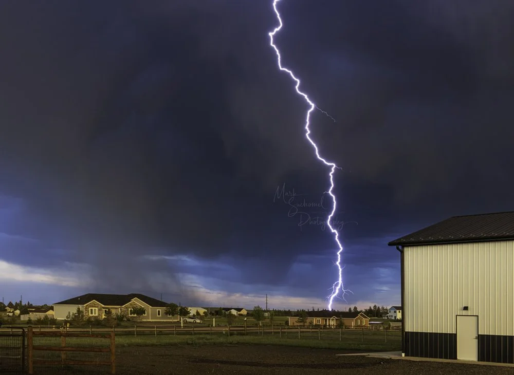 Cheyenne, Wyoming, a late afternoon thunderstorm moving over a residential neighborhood with a lightning strike 
