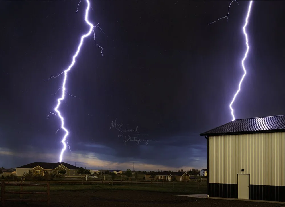 Cheyenne, Wyoming, a late afternoon thunderstorm moving over a residential neighborhood with a lightning strike reflected in the metal barn roof