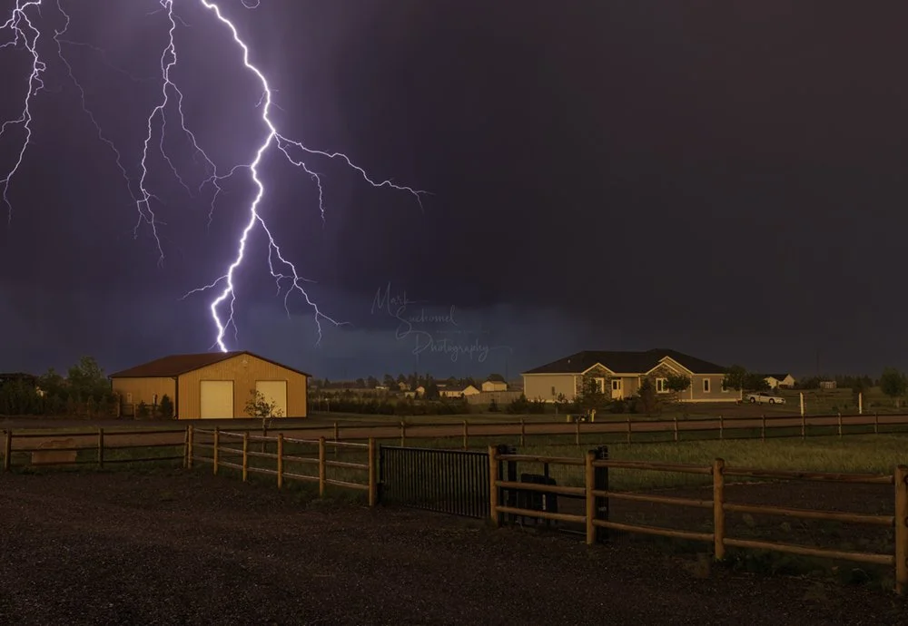 Cheyenne, Wyoming, a late afternoon thunderstorm moving over a residential neighborhood with a lightning strike 