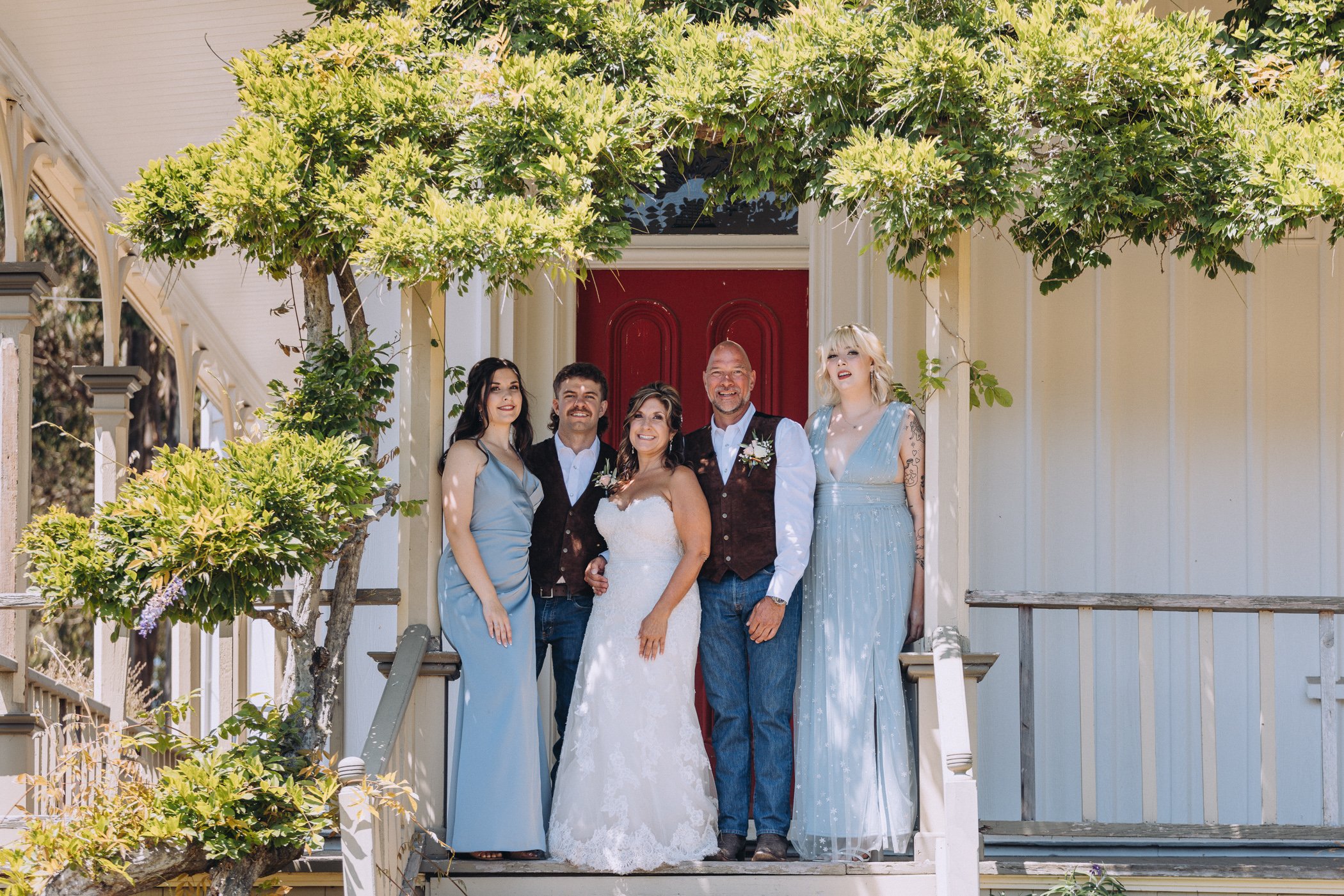Bride, groom, and friends in front of red door and white classic house at Spring Ranch, in Mendocino, Calfiornia