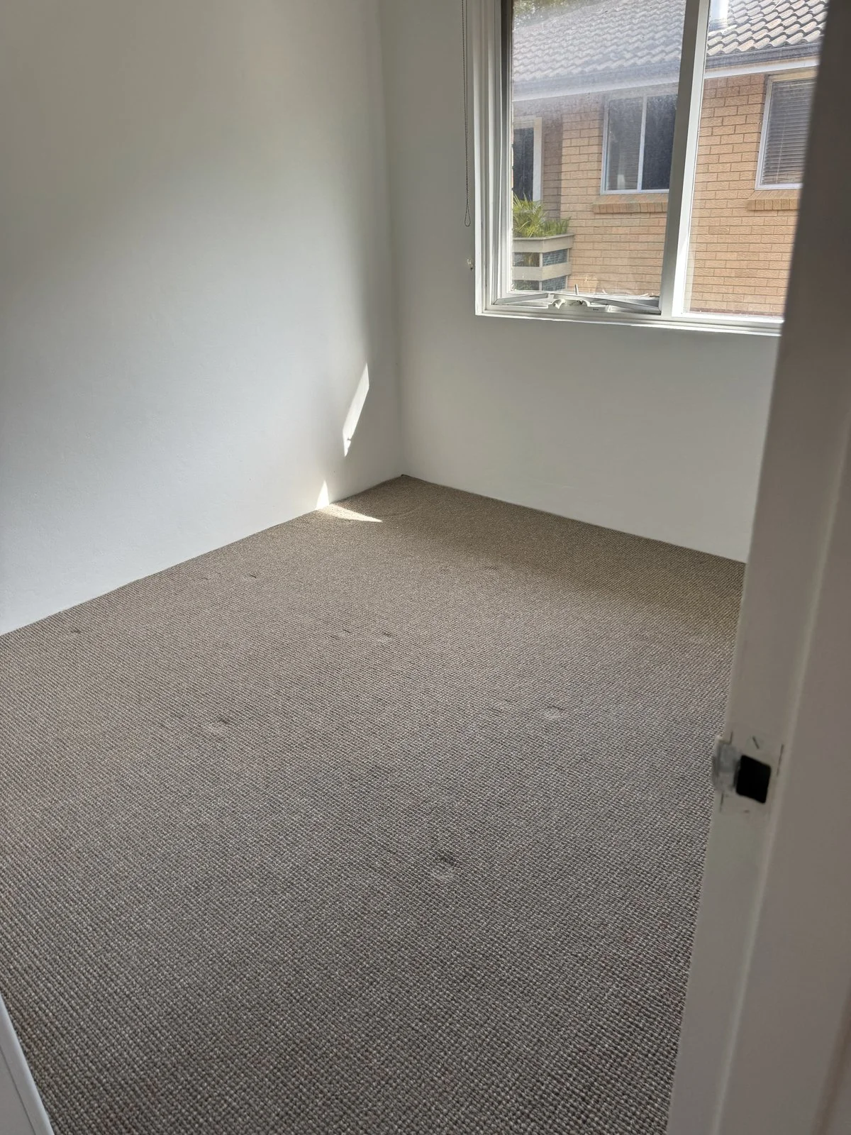 Empty wooden wall with three shelves, a built-in desk, and electrical outlets, in a modern room.