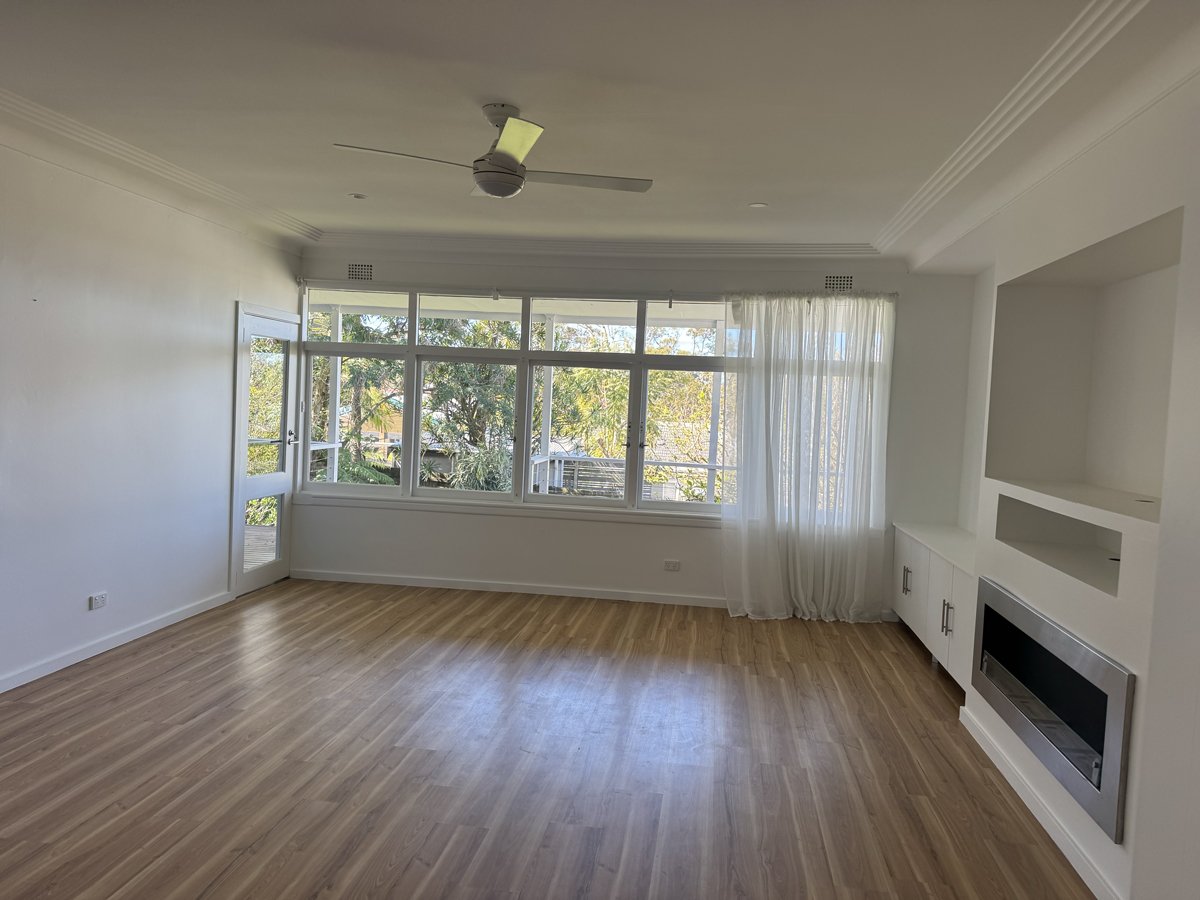 Empty wooden wall with three shelves, a built-in desk, and electrical outlets, in a modern room.