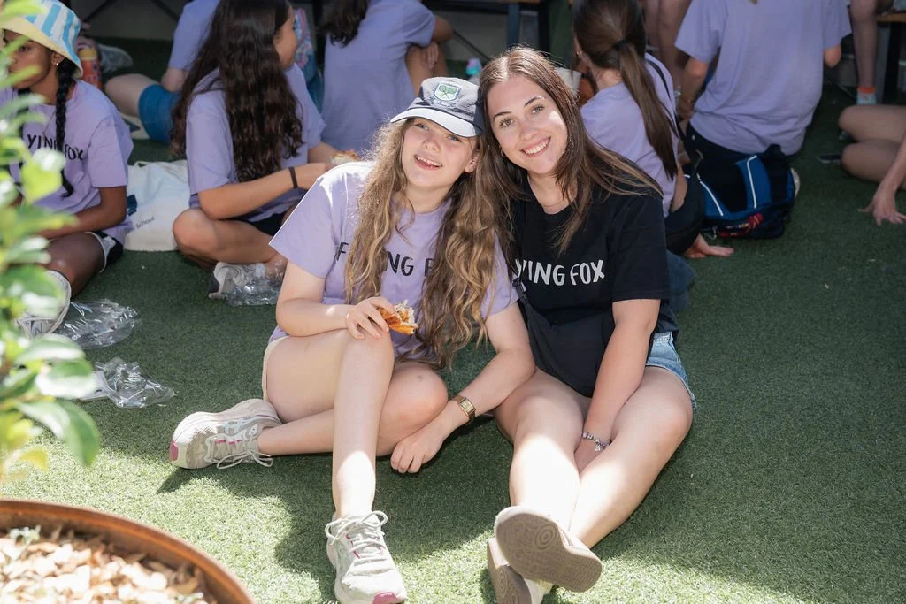 Two young females dress in purple sitting in the courtyard at Urban Camp