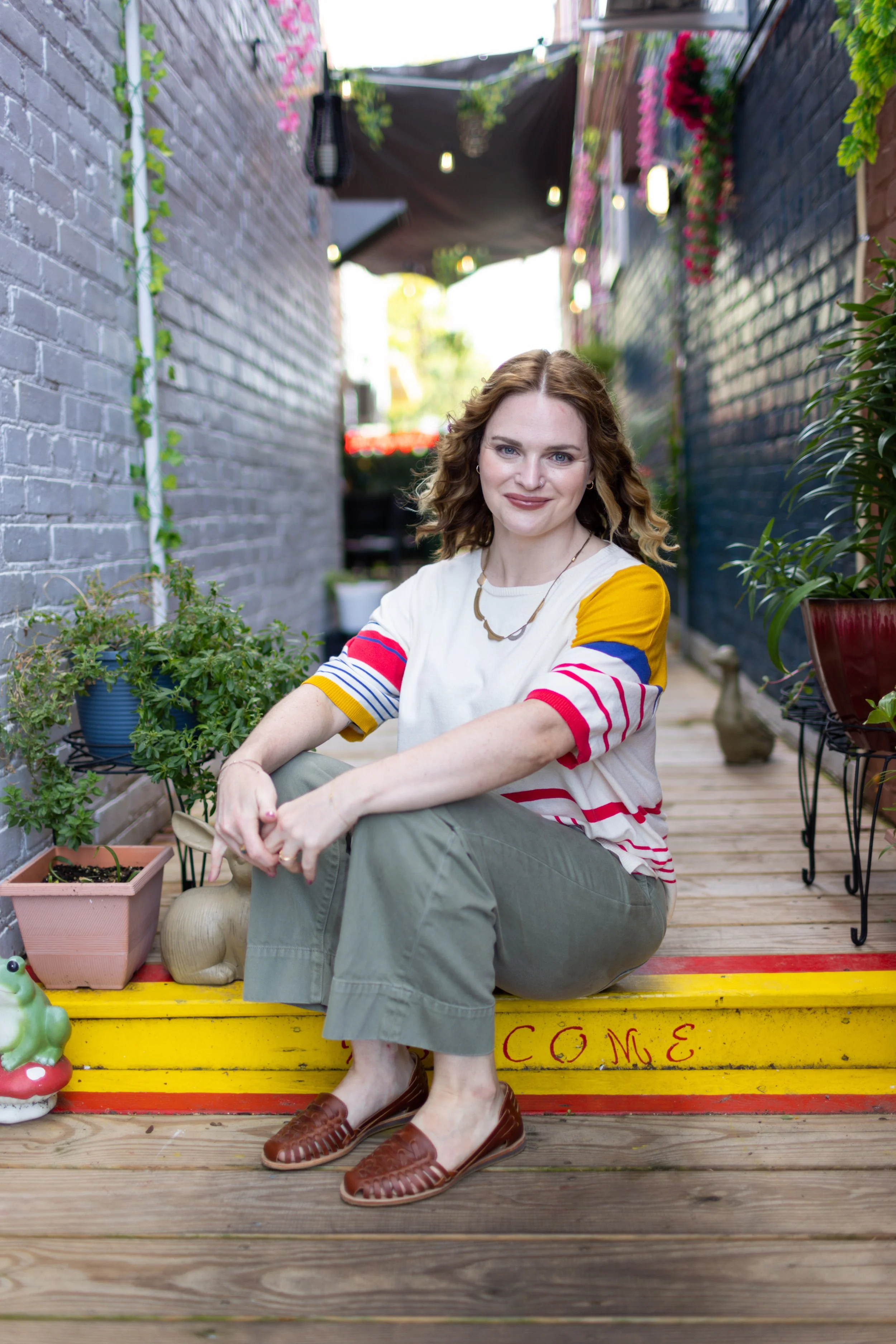 Moody, high-contrast lifestyle portrait photography of a woman sitting outside in a Richmond Virginia brick courtyard.